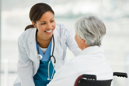Nurse checking on patient that is in a wheelchair.